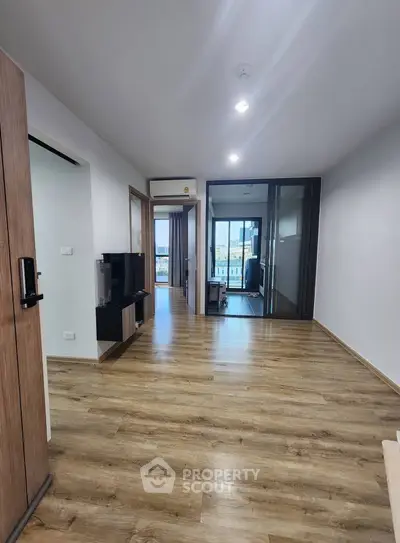 Modern apartment interior with wooden flooring and glass partition, featuring a spacious layout.