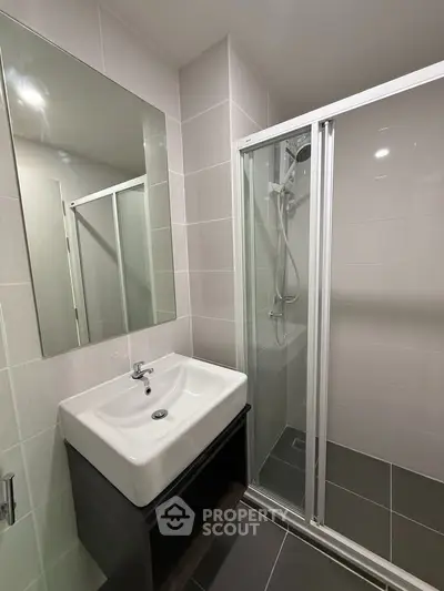 Modern bathroom with sleek shower and stylish sink in contemporary apartment.