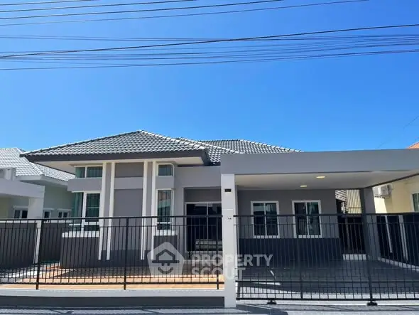 Modern single-story house with a spacious driveway and sleek design under a clear blue sky.