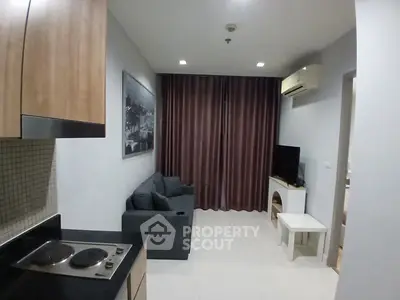 Modern living room with kitchenette, featuring sleek furniture and contemporary design.