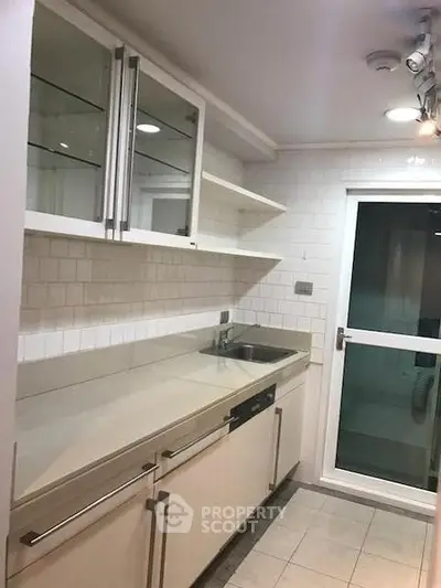 Modern kitchen with sleek cabinetry and glass shelves, featuring a compact layout and contemporary design.