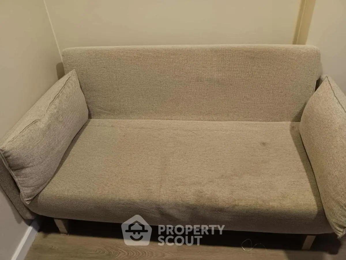 Cozy beige sofa in a compact living space with wooden flooring, perfect for small apartments.