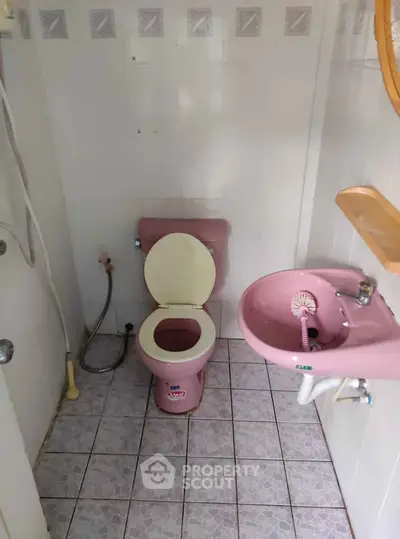 Charming vintage pink bathroom with matching sink and toilet, perfect for a retro touch.