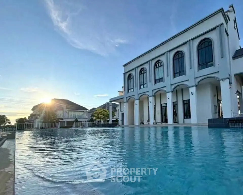 Luxurious mansion with stunning pool and elegant architecture at sunset.