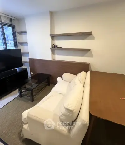 Cozy living room with modern furniture and wall-mounted shelves, perfect for relaxation and entertainment.