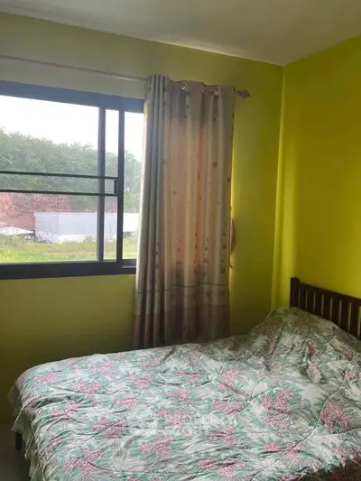 Cozy bedroom with bright yellow walls and floral bedding, featuring a large window with garden view.