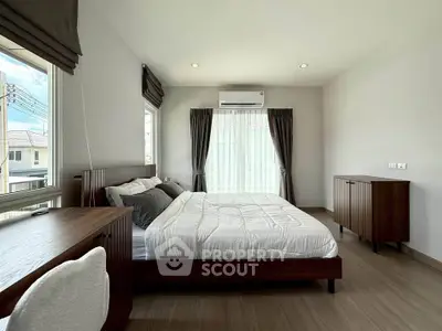 Spacious bedroom with modern furnishings and large windows offering natural light.