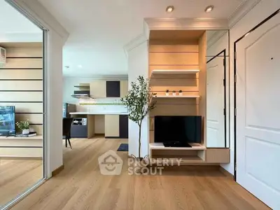 Modern open-plan living room with stylish wooden flooring and built-in TV unit