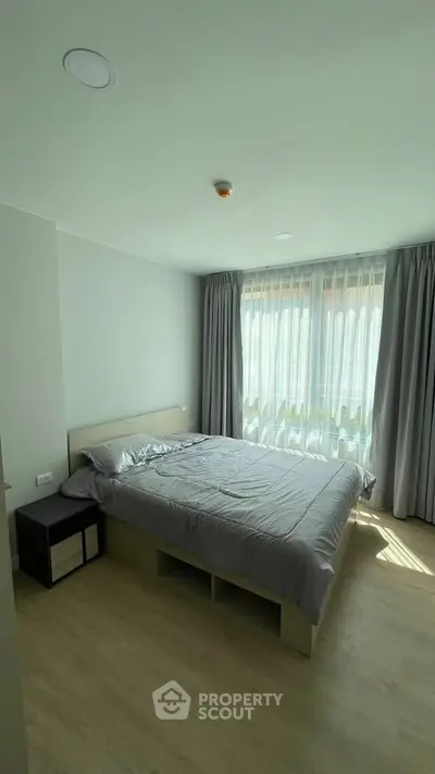 Bright and cozy bedroom with large window and modern furnishings