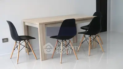 Modern dining area with sleek black chairs and wooden table in minimalist setting.