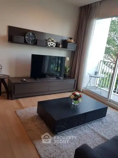 Modern living room with sleek furniture and large window opening to a balcony with a view.