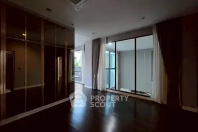 Spacious modern room with floor-to-ceiling windows and dark wood flooring