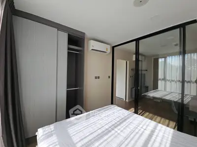 Modern bedroom with large windows and built-in wardrobe in a stylish apartment.