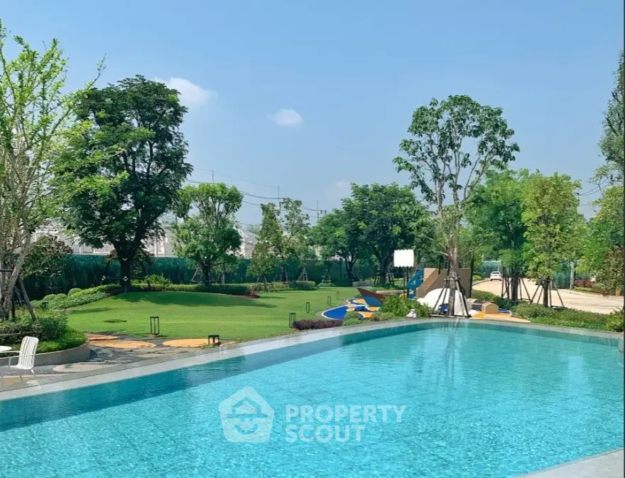 Luxurious outdoor pool with lush green surroundings and clear blue sky, perfect for relaxation and leisure.
