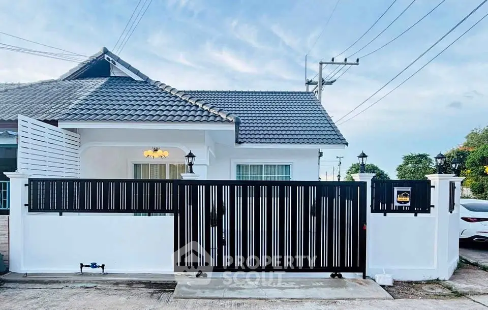 Charming single-story house with modern gate and tiled roof in serene neighborhood.