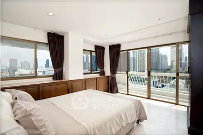 Spacious bedroom with city view and large windows in modern apartment