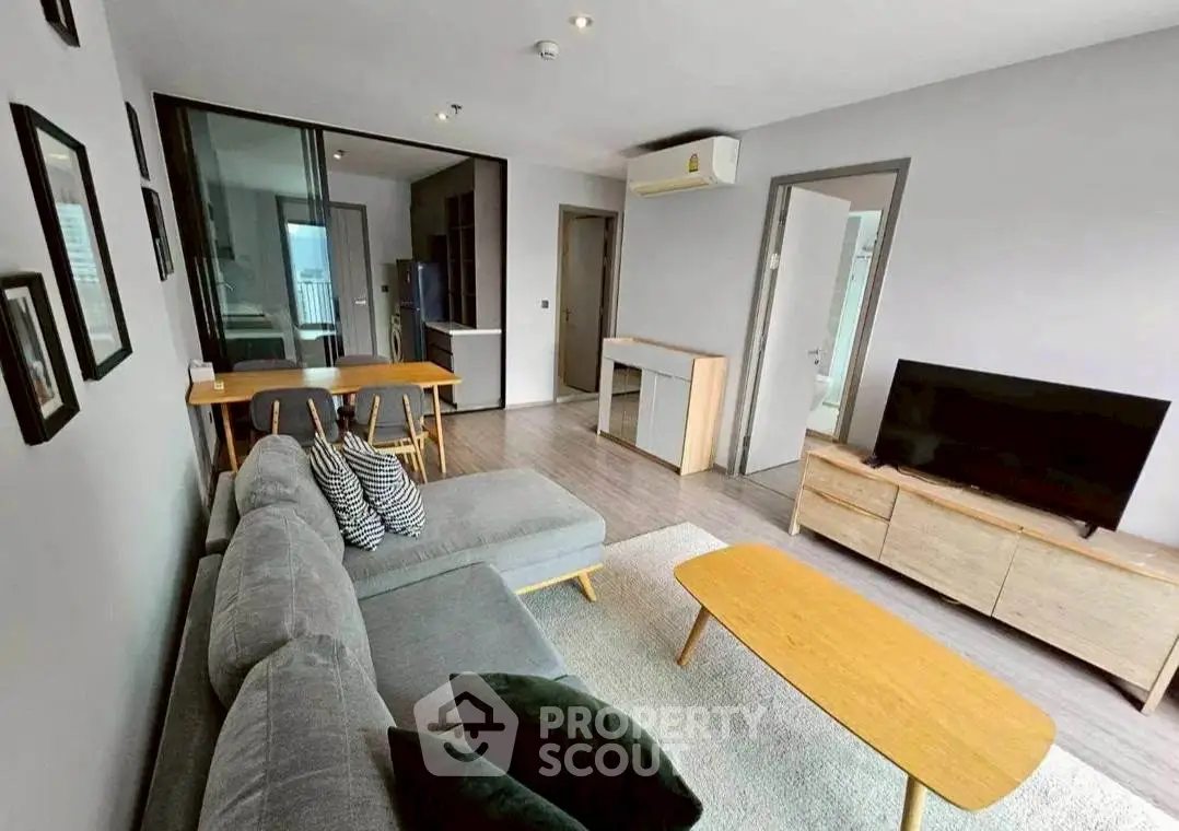 Modern living room with sleek furniture and open layout, featuring a cozy sofa and large TV.