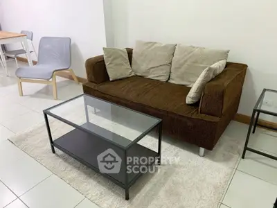 Cozy living room with modern brown sofa and glass coffee table on white tiled floor.