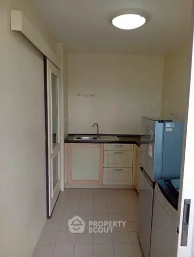 Compact kitchen with modern appliances and sleek cabinetry in a cozy apartment setting.