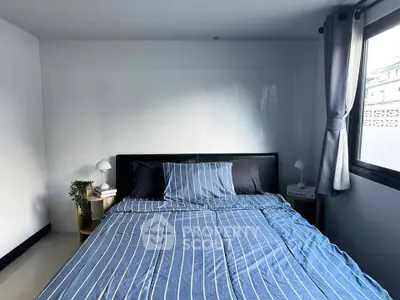 Cozy bedroom with striped bedding and natural light from window
