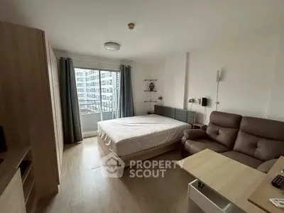 Modern studio apartment with cozy furnishings and city view balcony.