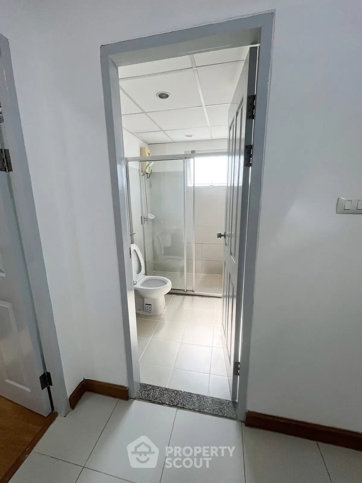 Modern bathroom with glass shower enclosure and sleek white tiles.