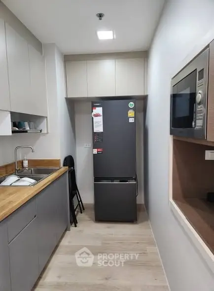 Modern kitchen with sleek appliances and wooden countertops in a compact layout.
