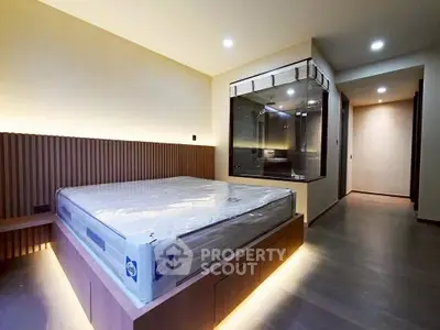 Modern bedroom with sleek design and ambient lighting, featuring a large bed and glass-enclosed bathroom.