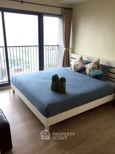 Spacious bedroom with large windows and a cozy bed, offering a serene view.