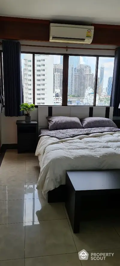 Modern bedroom with city view, featuring large windows and stylish decor in a high-rise apartment.