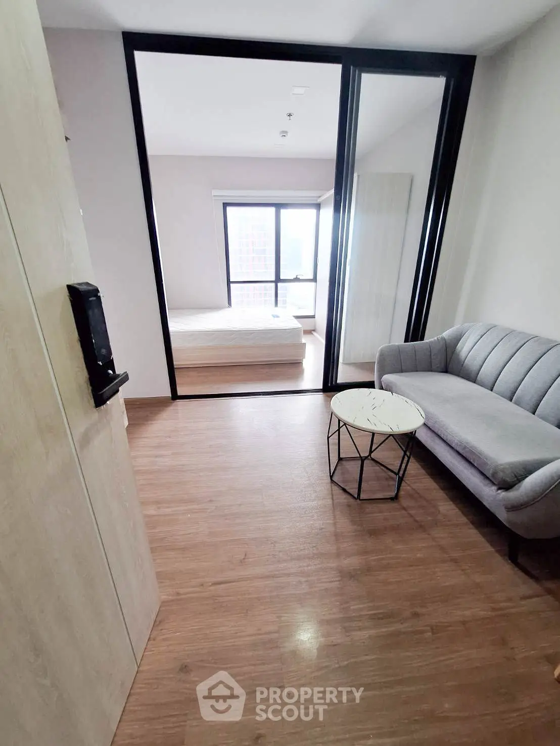 Modern apartment interior with cozy living area and bedroom, featuring stylish furniture and wooden flooring.