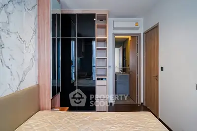 Modern bedroom with stylish wardrobe and marble accent wall in a contemporary apartment.