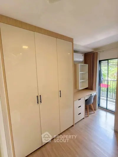 Modern bedroom with built-in wardrobe and study desk near balcony, featuring sleek design and natural light.