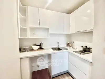 Modern compact kitchen with sleek white cabinets and integrated appliances