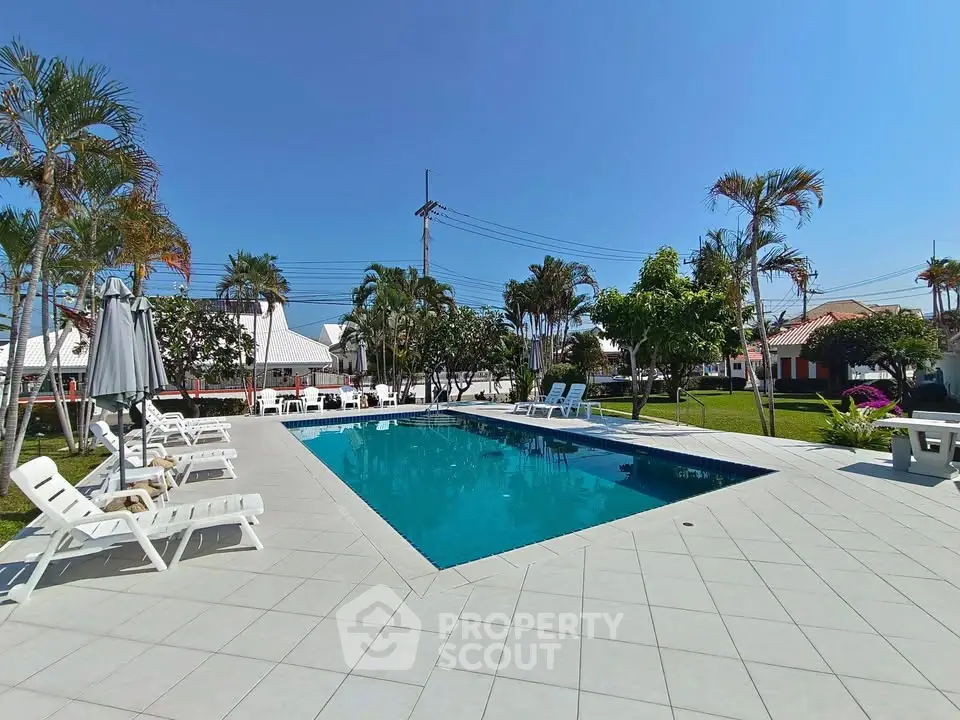 Stunning outdoor pool area with lush greenery and ample seating, perfect for relaxation and entertainment.