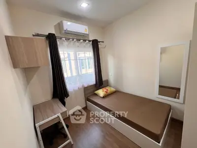 Cozy bedroom with single bed, desk, and air conditioning in modern apartment.