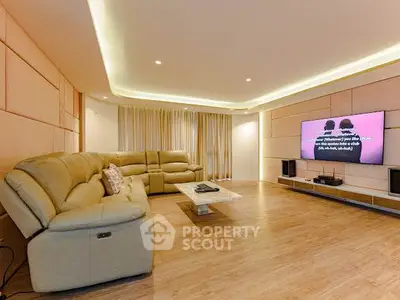 Spacious modern living room with luxurious leather sofa and large TV, perfect for entertainment.