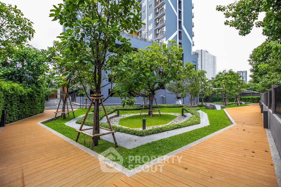 Modern apartment building with lush landscaped garden and wooden pathways.