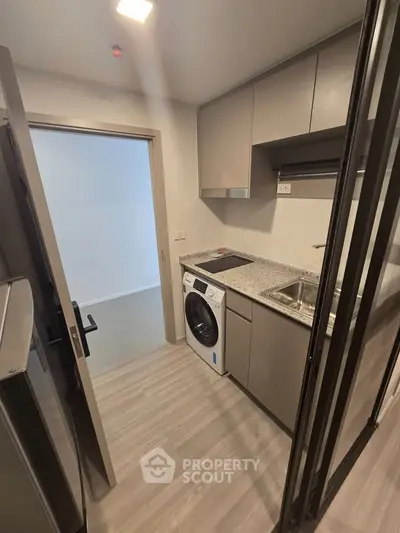 Modern kitchen with sleek cabinetry and built-in washing machine in a compact layout.