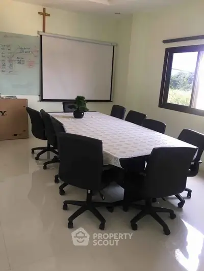 Spacious meeting room with large table and chairs, ideal for business gatherings.