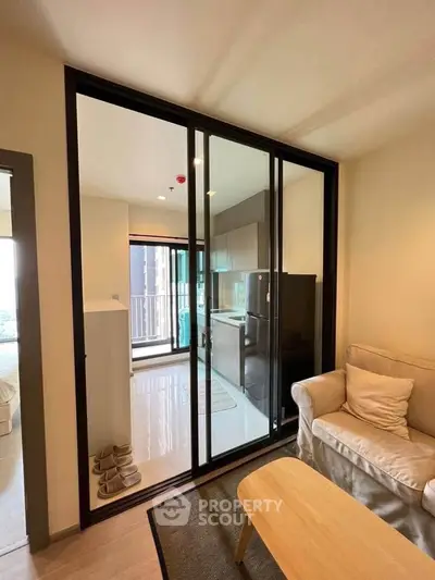 Modern apartment with open kitchen and cozy living area, featuring sleek sliding glass doors and natural light.