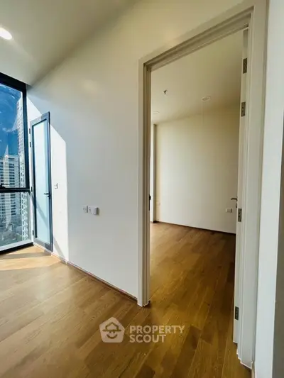 Bright modern apartment with wooden floors and large windows offering city views.