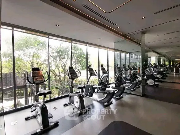 Modern gym with large windows and exercise equipment in luxury residential building.