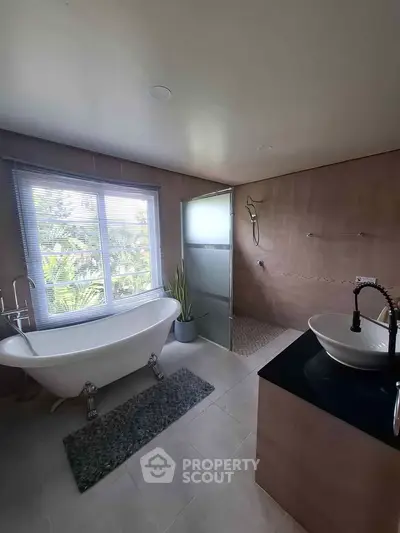 Luxurious bathroom with freestanding bathtub and modern fixtures, offering a serene view through large window.