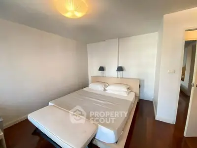 Spacious bedroom with modern lighting and wooden flooring in a stylish apartment.