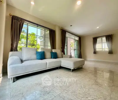 Spacious living room with large windows and modern sofa, offering abundant natural light and a serene atmosphere.