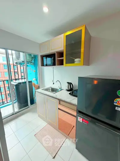 Modern compact kitchen with balcony view, featuring sleek appliances and stylish cabinetry.