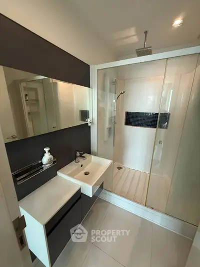 Modern bathroom with sleek shower and stylish vanity in contemporary apartment.