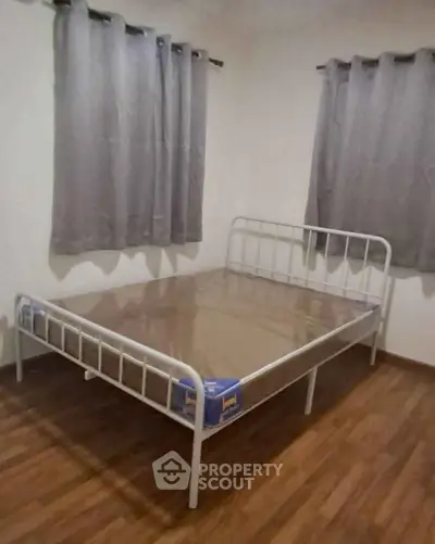 Cozy bedroom with metal bed frame and wooden flooring, perfect for minimalist living.