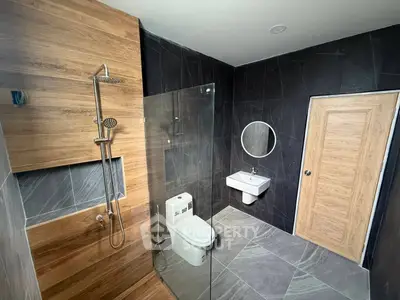 Modern bathroom with sleek design, featuring a glass shower and stylish wooden accents.